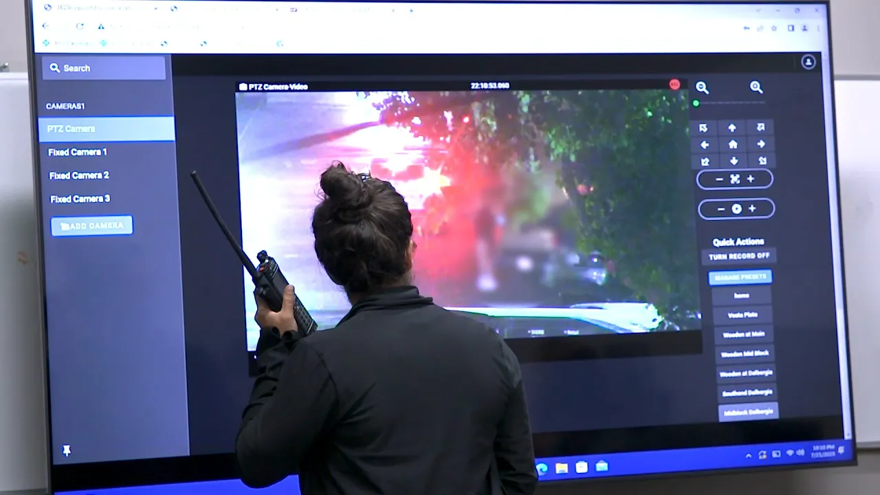 This is a still image from b-roll video of the 2023 iteration of the FBI's Operation Cross Country. The video shows a woman holding a walkie talkie while looking at video that's being projected onto a screen.