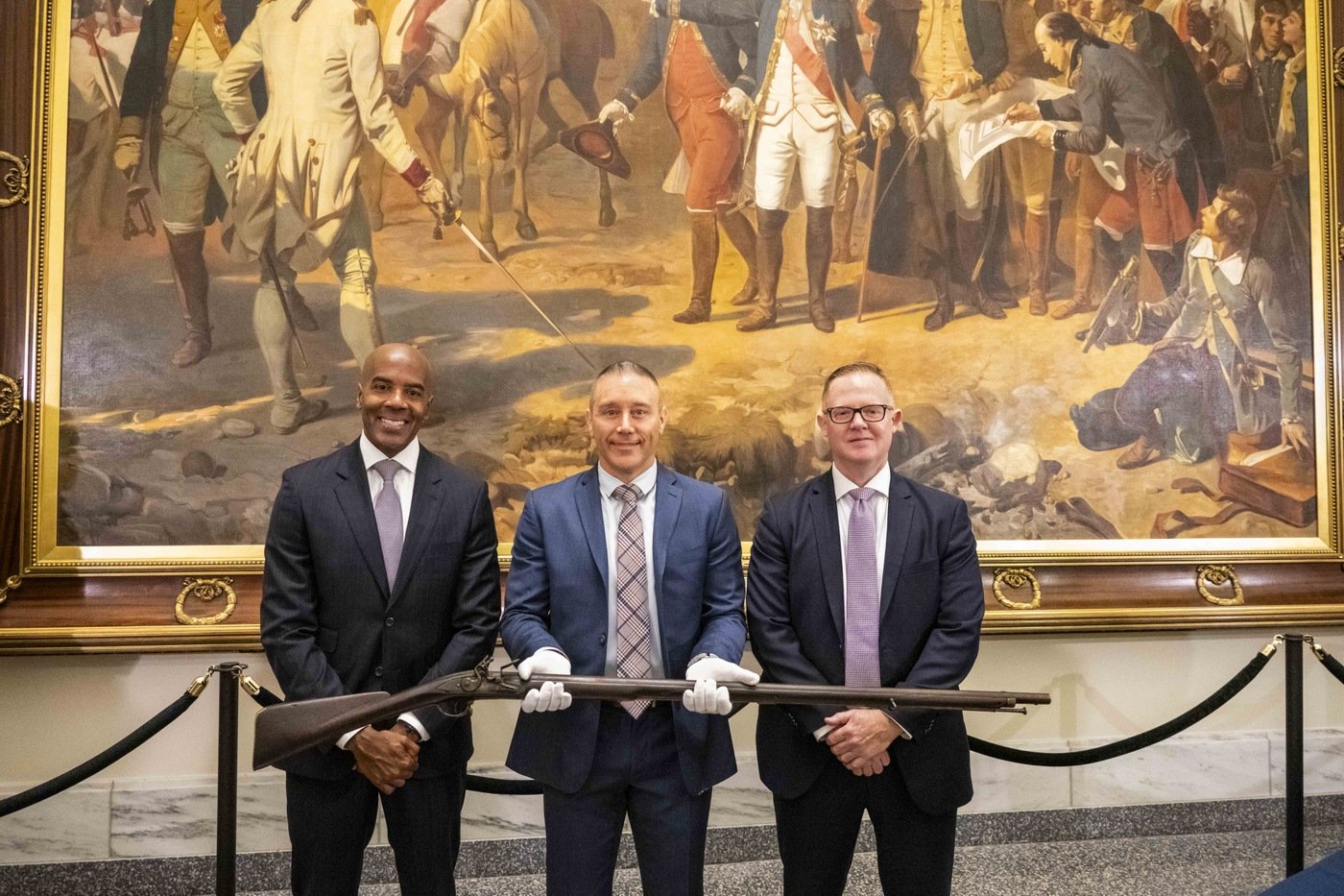 From left to right, FBI Philadelphia Special Agent in Charge Wayne A. Jacobs, Special Agent Jake Archer of the FBI Art Crime Team, and Assistant Special Agent in Charge Jamie Milligan pose with a Revolutionary War-era musket that was returned to the Museum of the American Revolution in Philadelphia on July 1, 2024.